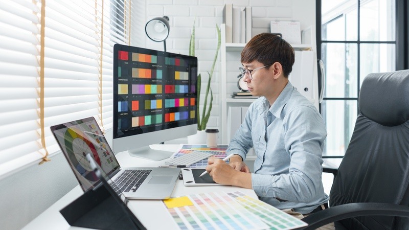 Man sits at computer to create a new design with a color wheel