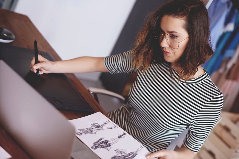 Woman sketches a new design using a digital pen with her computer