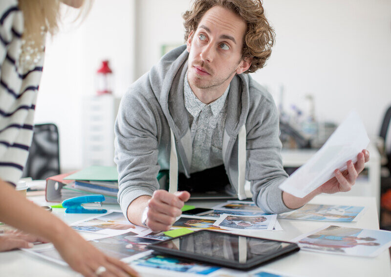 Young man uses tablet to lay out digital design for colleague